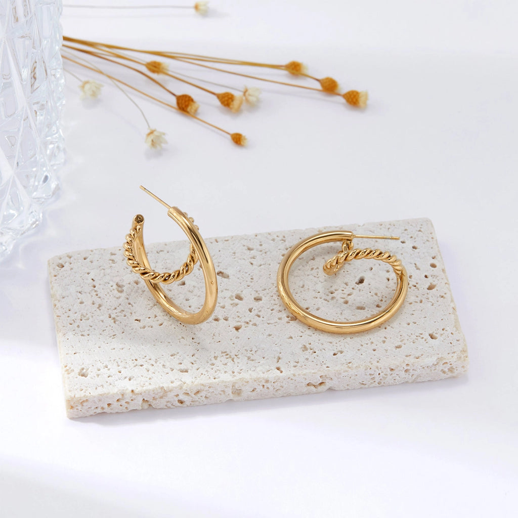The Shenita gold twisted hoop earrings styled on stone tray with dried florals