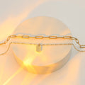 18K gold layered paperclip link and charm necklace on marble display