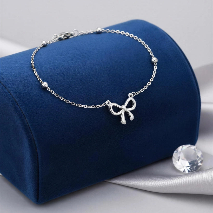 Bristol Bow Bracelet with dainty bow charm and polished bead accents on blue velvet display
