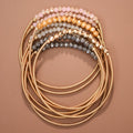 Mica Neutral Boho bracelet set with gold-tone spring coil bands and pink, cream, gray, and gold-tone beads