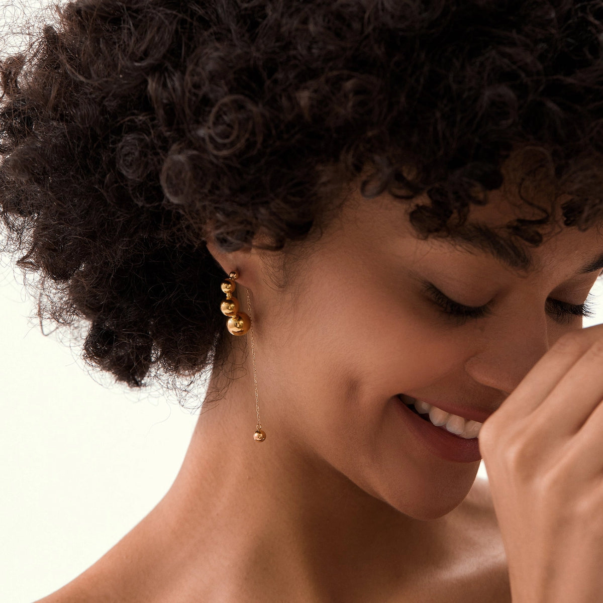 The Tracy gold ball chain drop earrings worn on model with curly hair