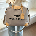 Caryall Cocoa work bag with tan handles and trim, black lettering, and a shoulder strap, held by a model
