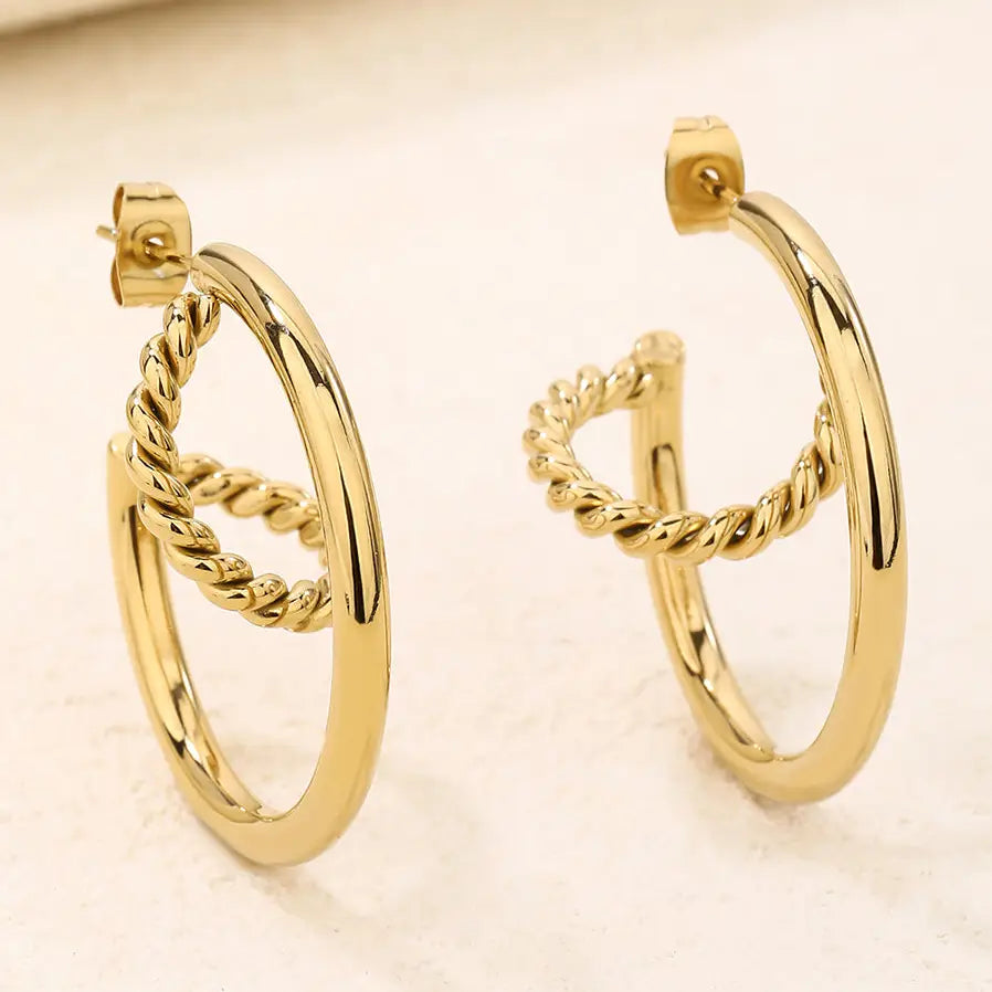 The Shenita chunky gold twisted croissant double hoop earrings on marble